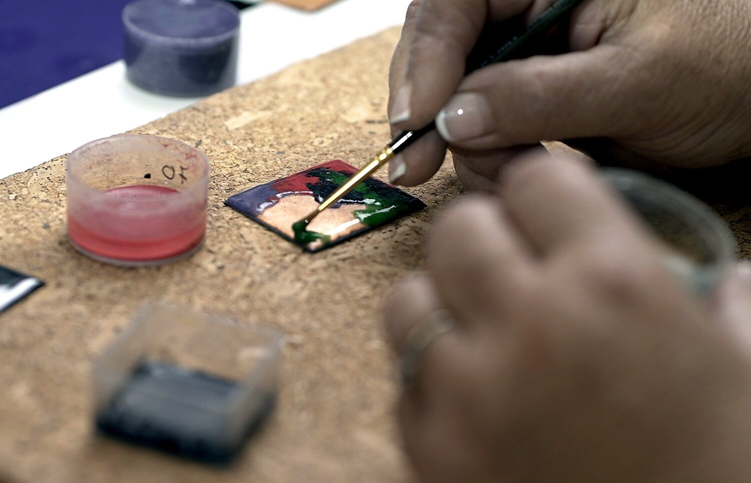 Pincel perfilando un rostro en una pieza de esmalte